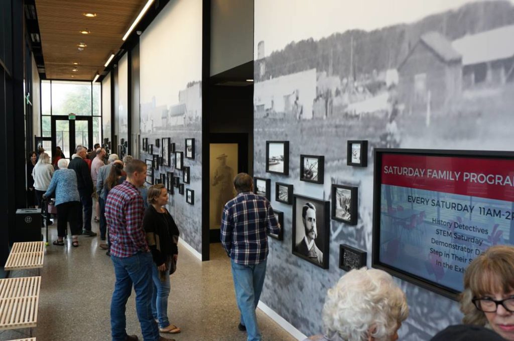 museum goers enjoy and read wall exhibits casually in hallway 