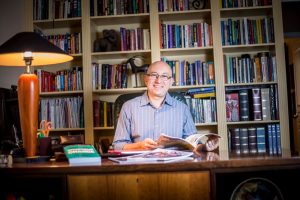 In the library of his south Tempe home, Dr. Flavio Marsiglia reviews the materials he utilizes to help individualize substance-abuse training in the communities his team visits. (Photo by Billy Hardiman/Wrangler News)